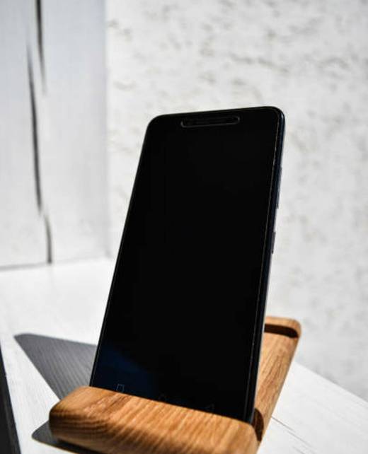 Black mobile phone stands on a wooden stand
